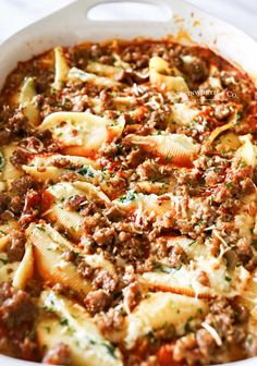 a white casserole dish filled with pasta and meat