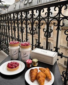 two plates with croissants, raspberries and yogurt sit on a balcony