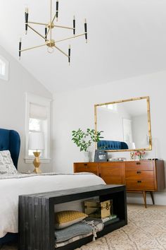 a bedroom with a bed, dresser and mirror on the wall next to it is a chandelier