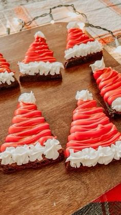 there are many small pieces of food on the wooden board with red and white frosting