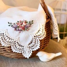 a close up of a basket on a table with a white cloth and some flowers