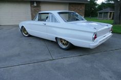 an old white car parked in front of a house