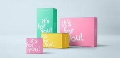 three colorful boxes with the words it's for you printed on them, one pink and one green