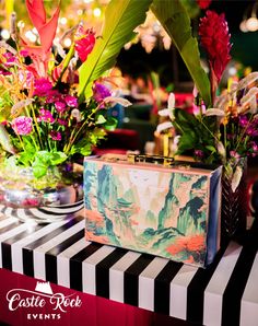 a suitcase sitting on top of a table next to vases with flowers in them