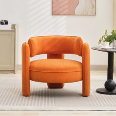 an orange chair sitting in the middle of a living room next to a small table