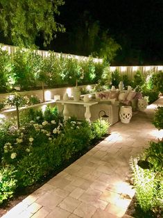 an outdoor patio area lit up at night with flowers and greenery on the side