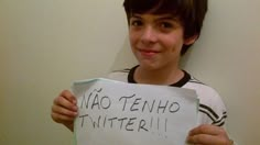 a young boy holding up a sign that says nao tenho twitterr