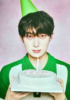 a young man holding a cake with a candle in it