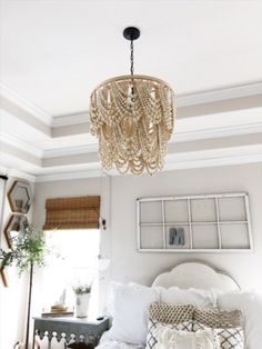 a bedroom with a chandelier hanging from the ceiling and pillows on the bed