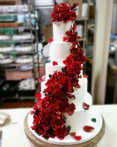 a three tiered cake with red flowers on it