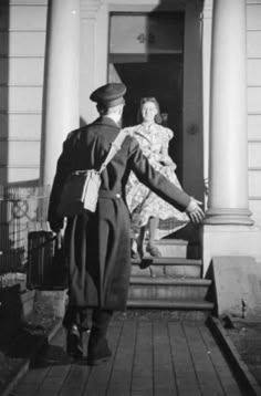 an old black and white photo of two people in front of a building with columns