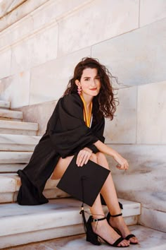 a woman is sitting on the steps in her graduation gown