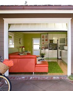 a bicycle is parked in front of a garage with an orange couch and coffee table