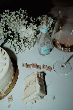 there is a cake, wine glass and bottle on the table next to each other