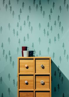 a wooden dresser sitting next to a wall with pine trees painted on the wall behind it