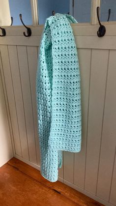 a blue crocheted sweater hanging on a coat rack