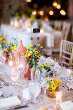 the table is set with flowers, candles and wine glasses for an elegant wedding reception