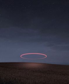 a red circle is in the middle of a field at night with stars above it