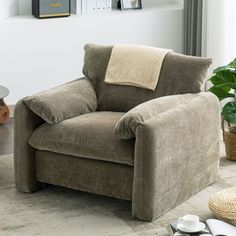 a living room with a chair, coffee table and potted plant on the floor