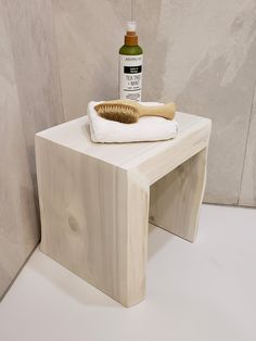 a wooden stool with a white towel on top of it next to a bottle of shampoo