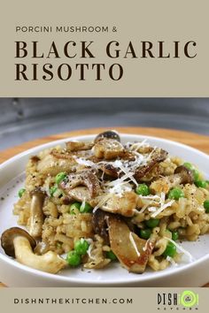 black garlic risotto with peas and mushrooms on a white plate over a wooden table