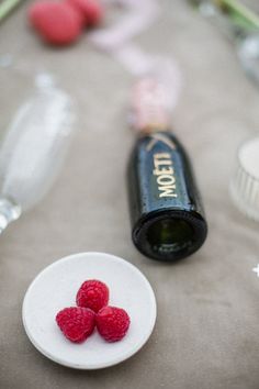 raspberries on a plate next to a bottle of wine