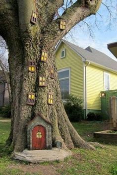 a tree that has some kind of house on it's trunk in front of a yellow house