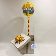 a birthday balloon sitting on top of a box next to a bunch of candies