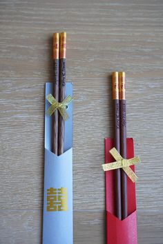 two pencils are wrapped in paper and tied with gold ribbon on top of each other