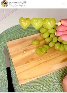 someone is cutting grapes on a wooden board