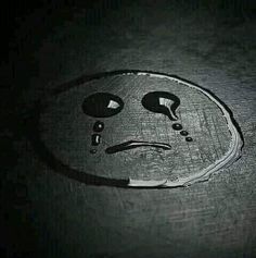 a smiley face drawn in the middle of a dark surface with two eyes and one nose