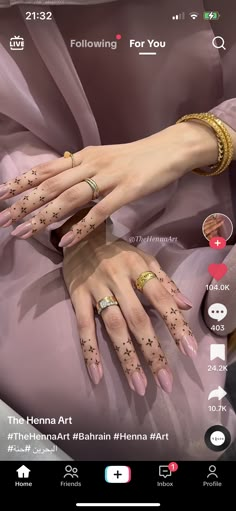 two women's hands with henna tattoos on their fingers and the other hand is holding