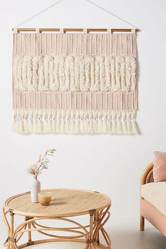 a table with a plant on it in front of a wall hanging