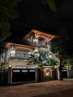 a large white house sitting on top of a lush green hillside at night with lots of lights