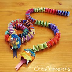 an origami bird made out of colored paper on a wooden table with the words craftimens written below it