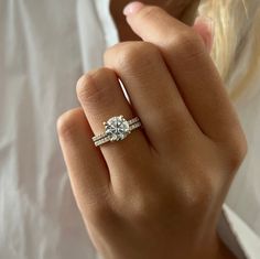 a woman's hand with a diamond ring on top of her finger and an engagement band