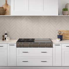 a stove top oven sitting inside of a kitchen next to white cabinets and counter tops