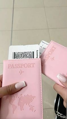 a person is holding two pink passport cases