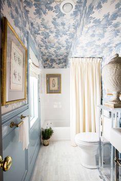 a white toilet sitting next to a bath tub under a painting on the wall in a bathroom