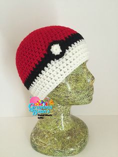 a red, white and black crocheted hat on top of a mannequin head