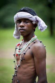 a young man with no shirt wearing beads and a headdress