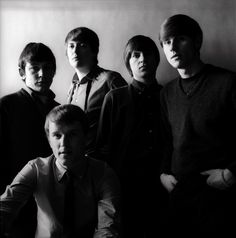 a group of young men standing next to each other in front of a white wall