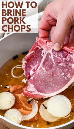 a person is holding a piece of raw pork in a bowl with onions and broth