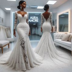 two women standing in front of a mirror wearing wedding dresses with long sleeves and open back