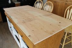 a kitchen island made out of plywood with chairs around it