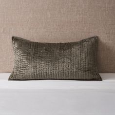 a pillow sitting on top of a bed next to a headboard with a beige wall behind it