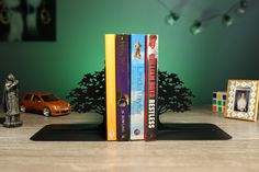 three books are stacked on top of each other in front of a toy car and tree