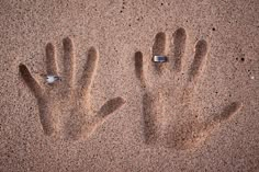 two hand prints in the sand next to each other with an arrow pointing up at them