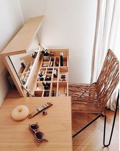 a wooden table topped with lots of drawers filled with jewelry next to a chair and window