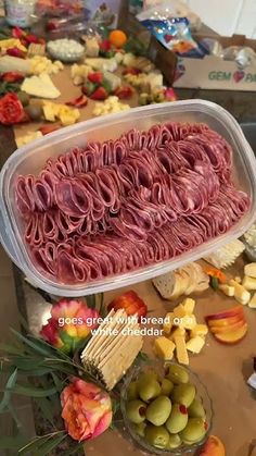 an assortment of meats and cheeses displayed in plastic containers on a buffet table